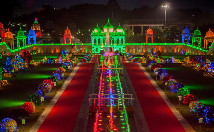Illuminated Badshah and Begum wedding theme setup at Ramoji Film City Hyderabad with vibrant domes, red carpets, and glowing gardens at night.